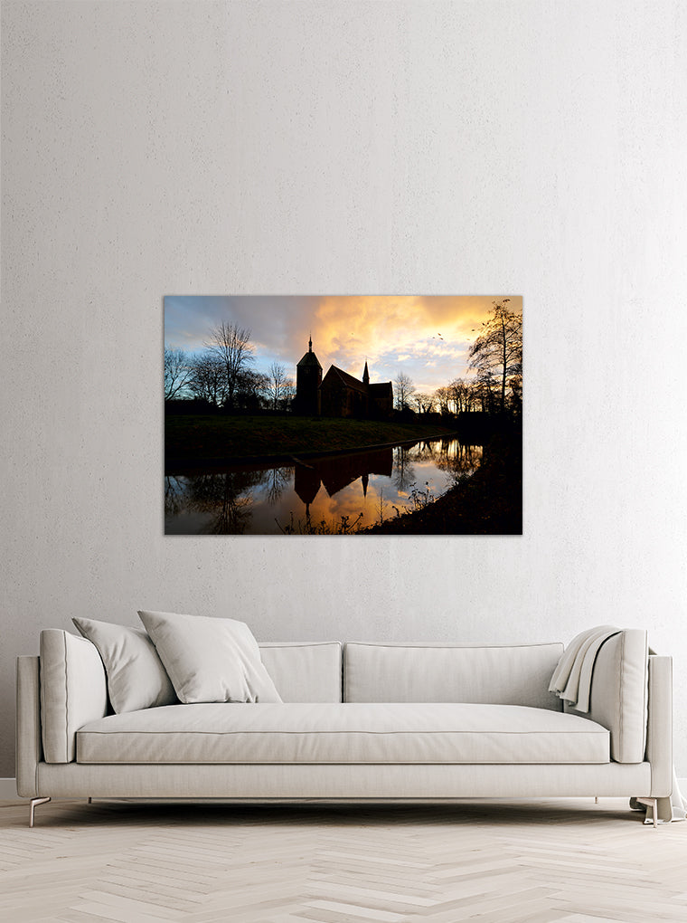 Darstellung eines Art Prints der Heimatlinse hängend an einer Wand in heller Umgebung mit Motiv von Kirchen-Silhouetten bei Abendstimmung.
