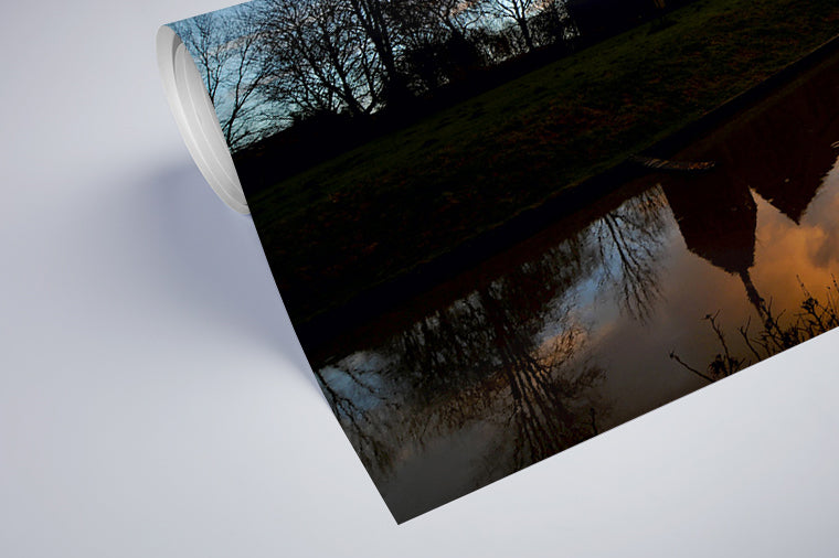 Darstellung eines Art Prints der Heimatlinse als halb aufgerolltes semi-mattes Poster mit Motiv von Kirchen-Silhouetten bei Abendstimmung.