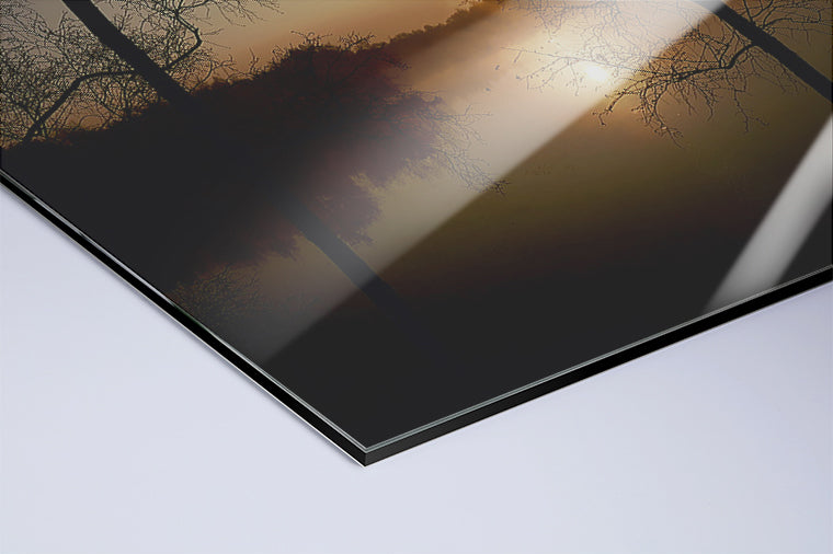 Darstellung eines Art Prints der Heimatlinse als hochglänzender UV-Direktdruck auf Aluverbund mit Motiv eines Sonnenaufgangs und dunklen Silhouetten am See.